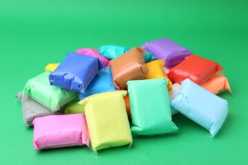 Different colorful play dough in packages on spring green background, closeup