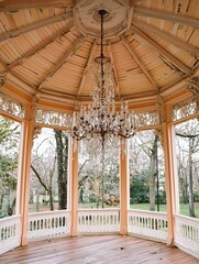 Fototapeta premium Elegant gazebo interior featuring a chandelier and wood detailing in a serene park setting.