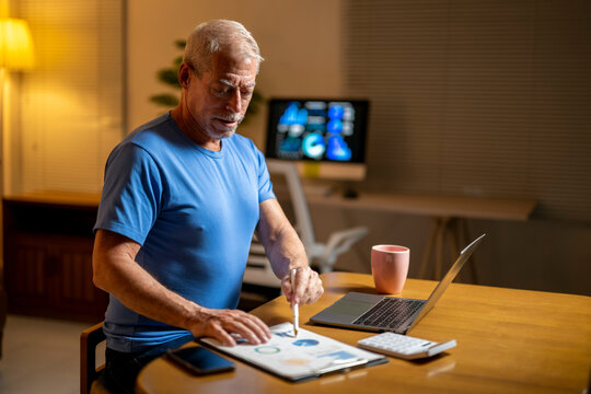 A man in a blue shirt is sitting at a table with a laptop and a tablet