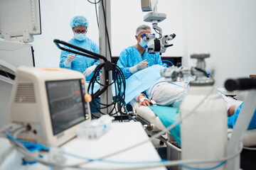 Skilled surgeon and his medical team performs precise eye surgery on an elderly patient, restoring...
