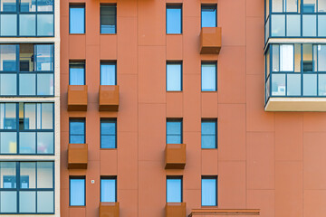 Modern apartment building facade with orange walls and blue windows in contemporary style