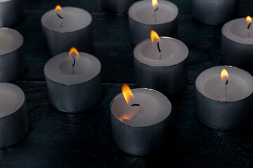 Tea light candles on a dark background, many lights in the dark, candlelight