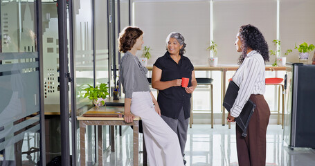 Indian young adult women intern old aged lady hold cup mug drink coffee talk gossip work place expert teen girl staff group team speak idea blab share enjoy fun joy tea break day spend time job office