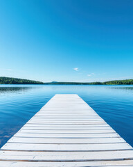 Naklejka premium serene wooden dock extends into calm lake under clear blue sky