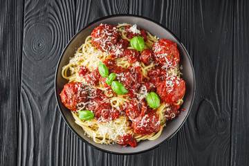 delicious traditional Italian meatballs polpette with spaghetti pasta on a black wooden rustic background