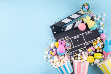 Obraz premium Easter film and movie background. Cinema clapper-board with Easter chocolate egg. popcorn and marshmallow, Cinema for the Easter holidays and Movie Night party