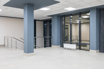 panorama view in empty modern office hall with columns, doors, stairs and panoramic windows at night