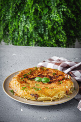 traditional Italian omelet with spaghetti frittata on a stone rustic background