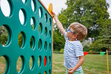 Boy plays giant Connect Four outdoors, enjoying the fun game