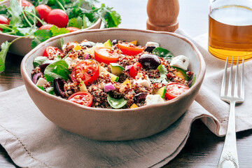 Quinoa salad, healthy Mediterranean lunch with fresh organic vegetables, cheese, and olives, with olive oil