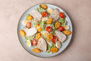 Caesar salad with chicken, cherry tomatoes, croutons, parmesan cheese, quail eggs and romaine lettuce. Traditional American dish. Close-up, selective focus.