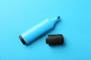 Bright highlighter and cap on light blue background, flat lay