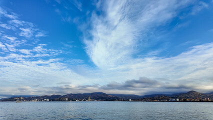 Seascape with feathery clouds on the background of mountains