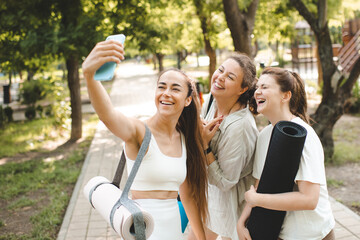 Smiling happy women 30-35 year old making selfie after yoga class in park outdoor. Summer season.