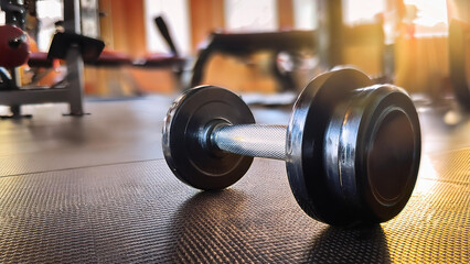 Close-up of a Dumbbell on the Gym Floor: Soft Lighting and a Blurred Background for Focus on the Equipment        