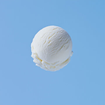 A perfectly round scoop of vanilla ice cream floating in mid-air