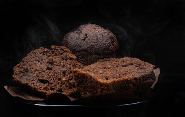 Sliced chocolate muffin on dark background. Steam comes out of fresh chocolate muffin.