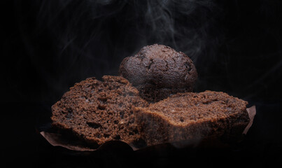 Sliced chocolate muffin on dark background. Steam comes out of fresh chocolate muffin.
