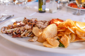 Tender squid cooked on a pan with crispy fried potatoes, representing a classic Mediterranean meal popular in seaside seafood restaurants