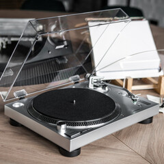 A turntable with a black record on it sits on a wooden table