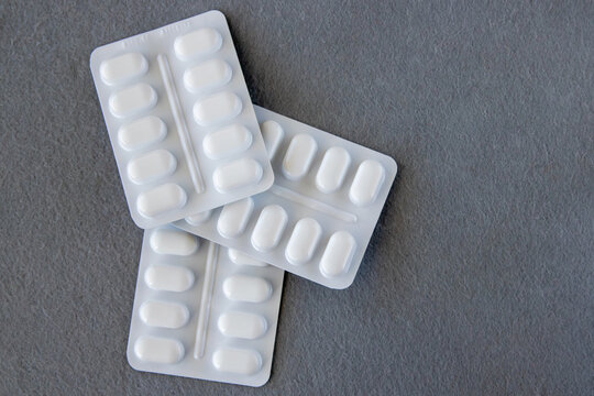 Tabletten or pillen in white package on the gray background with place for text.