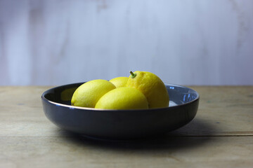 Lemons in a bowl on a wooden table and white background