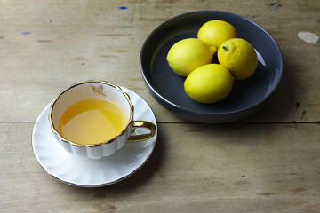 Lemons and cup of tea on wooden table, still life