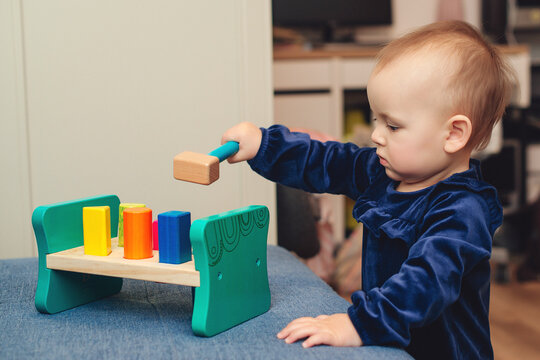 Cute baby girl playing with wooden toys. Toys for small children. Child with an educational toy. Happy childhood.