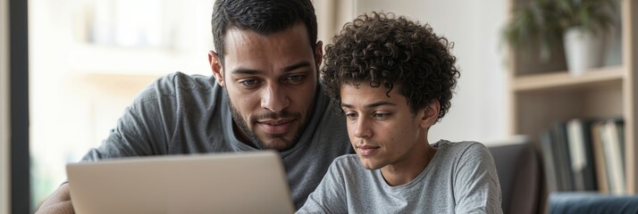 Father and Son Collaboration. A man and a teenage boy focused on a laptop, working together in a cozy home setting with a supportive and collaborative atmosphere.