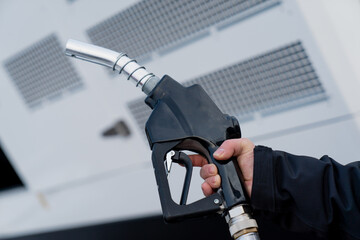 Man holding black diesel gasoline pistol a gas center. High prices on fuel energy, man can not...