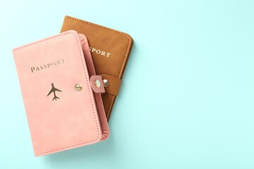 Two passports in bright covers on turquoise background, top view. Space for text