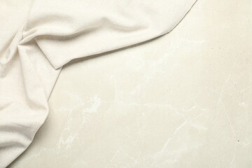 Beige tablecloth on light gray textured background, top view. Space for text