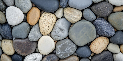 Natural river stone background with smooth, rounded pebbles in shades of gray, beige, and brown, polished by water over time.