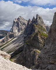 Sharp peaks of Seceda Ridge in the Dolomites, Italy, framed by steep cliffs and rocky textures. A dynamic alpine view under a partly cloudy sky