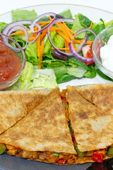 Quesadilla, Mediterranean salad, salsa and sour cream Mexican style food plate