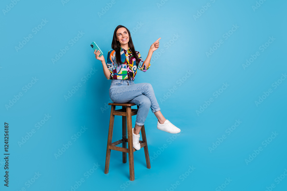 Poster full size photo of positive girl dressed blouse sit on chair hold smartphone look directing empty sp