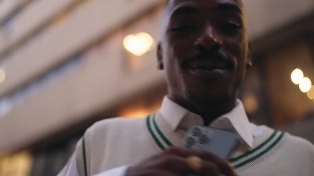 stylish African American man energetically performs rap while hold smartphone,expressing creativity and passion.Male confident smile and dynamic gestures capture essence of urban music culture in city