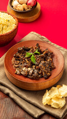 Fried beef lung, A beautifully presented dish of rich, spiced meat alongside rice and crispy chips, set against a bright red backdrop