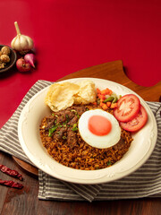 Indonesian rendang fried rice, A vibrant dish of fried rice featuring tender beef, a perfectly cooked fried egg, and fresh vegetables presented on a rustic wooden board
