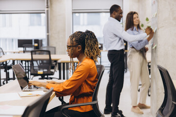 Colleagues collaborating, working individually and together in contemporary workspace, displaying...