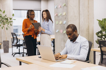 Professional team collaborating, using digital devices in modern workspace, driving innovative solutions and workplace synergy