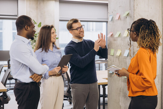 Collaborative team brainstorming project strategy, using multicolored sticky notes in modern bright office environment