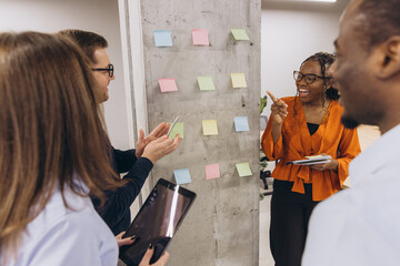 Diverse businesspeople brainstorming new ideas using colorful sticky notes during a productive...