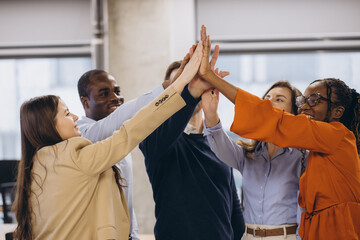 Diverse business team connecting hands, expressing unity and achievement in contemporary workplace...