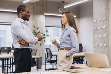 Two managers enjoying a coffee break, engaging in lively discussions and sharing ideas in a vibrant, modern office environment