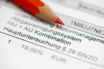 Fototapeta premium Ein Rotstift liegt auf der Rechnung zur TÜV-Hauptuntersuchung und Abgasmessung - Symbolbild