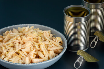 Canned shredded jackfruit in a bowl and two empty tins on the side. Great vegan substitution for chicken. 