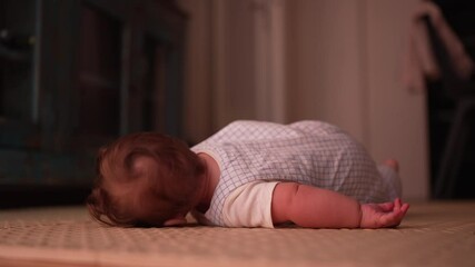 Baby looking down during tummy time, focusing on movement and exploring surroundings, early developmental milestone, natural play on floor in comfortable home environment