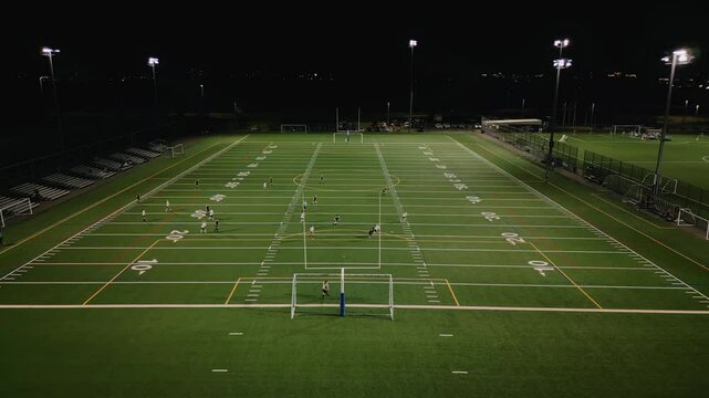 A Stunning Aerial View Of Two Women Soccer Teams Playing Football At Night In Dartmouth, Nova Scotia. The Late-Night Practice Demonstrates The Hard Work And Determination Of Young Athletes. 