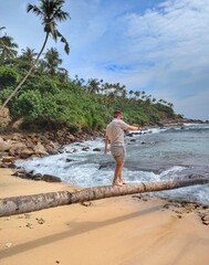 A man balances on a tree branch over the waves at Secret Beach near Mirissa, Sri Lanka.